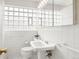 Bright bathroom with white tile, a glass block window, a pedestal sink, and accessible grab bars at 1030 Krameria St, Denver, CO 80220