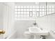 Bright white bathroom featuring tile, sink, toilet, glass block window and shower at 1030 Krameria St, Denver, CO 80220