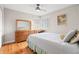 Cozy bedroom featuring a ceiling fan, hardwood floors, shuttered windows, and large wooden dresser with a mirror at 1030 Krameria St, Denver, CO 80220
