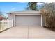 Detached garage with a gray door and concrete driveway, enhanced by a well-maintained white picket fence at 1030 Krameria St, Denver, CO 80220