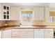 Well-lit kitchen with white cabinetry, tile backsplash, and a view through the window at 1030 Krameria St, Denver, CO 80220