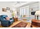 Comfortable living room with hardwood floors, white bookshelves, bright window with shutters, and a blue recliner at 1030 Krameria St, Denver, CO 80220