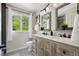Bright bathroom features a double sink vanity, wood-look tile floor and a large window overlooking the backyard at 11453 E Orchard Pl, Englewood, CO 80111