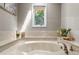 Luxurious soaking tub with marble surround, stylish fixtures, and a bright window overlooking the outdoor scenery at 11453 E Orchard Pl, Englewood, CO 80111