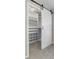 Custom closet design with white barn door, open shelving, drawers, and clothing racks at 11453 E Orchard Pl, Englewood, CO 80111