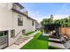 A modern backyard with a pergola, turf, patio chairs and a staircase to an upper level at 220 Glencoe St, Denver, CO 80220