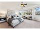 Bright main bedroom with large windows, neutral walls, cozy bedding and a seating area at 2412 Windmill Dr, Longmont, CO 80504