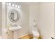 Well-lit half bathroom features hardwood floors, modern toilet, and decorative mirror above a pedestal sink at 58 Rogers Ct, Golden, CO 80401