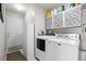 Bright laundry room with white washer and dryer set, upper storage cabinets, and access to the exterior at 5133 S Liverpool Way, Centennial, CO 80015