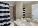 Bathroom with shower and tub, toilet, sink with mirror, and striped shower curtain at 5546 S Quemoy Cir, Aurora, CO 80015