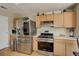 Modern kitchen with stainless steel appliances, light wood cabinets, and an island at 5546 S Quemoy Cir, Aurora, CO 80015