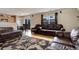 Spacious living room with hardwood floors, brown leather furniture, and large windows at 5546 S Quemoy Cir, Aurora, CO 80015