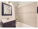 Updated bathroom featuring a dark vanity, large mirror, and tub with tile surround at 5150 W Colgate Pl, Denver, CO 80236