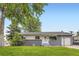 Well-maintained single-story home with a gray brick and white facade and green lawn at 5150 W Colgate Pl, Denver, CO 80236