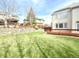 Backyard with a well-maintained lawn, stone retaining wall, wooden fence, and a small deck at 6459 S Queen Way, Littleton, CO 80127