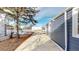 Long driveway alongside blue siding with a mature tree, fence and view of neighbor's home at 3282 W 66Th Ave, Denver, CO 80221