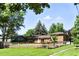 Beautifully landscaped backyard with mature trees, a well-maintained lawn, and a white picket fence creating a serene outdoor space at 1380 Holly E Dr, Broomfield, CO 80020