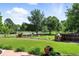 Landscaped backyard featuring a manicured lawn, mature trees, and a charming playhouse at 1380 Holly E Dr, Broomfield, CO 80020