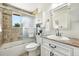 Bright bathroom featuring a shower-tub with glass door, vanity with marble countertop, and white cabinets at 1380 Holly E Dr, Broomfield, CO 80020
