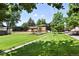 Well-maintained front yard with mature trees, a lush green lawn, and a charming home exterior at 1380 Holly E Dr, Broomfield, CO 80020