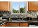 Close-up of the kitchen sink area with mosaic backsplash and views of the greenery outside at 1380 Holly E Dr, Broomfield, CO 80020