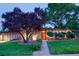 Mid-century modern home with well-lit stone facade, mature landscaping, and a walkway at 3650 Chimayo Rd, Littleton, CO 80123
