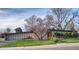 Lawn view of mid-century home featuring stone facade and mature landscaping at 3650 Chimayo Rd, Littleton, CO 80123