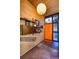 Mid-century modern foyer boasts a unique wooden wall unit and orange front door at 3650 Chimayo Rd, Littleton, CO 80123
