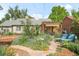 Picturesque backyard featuring a stone patio, pergola, colorful flowers, and lush landscaping at 1185 Glencoe St, Denver, CO 80220