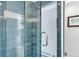 Bathroom shower featuring tiled walls, corner shelves, and a glass door at 1185 Glencoe St, Denver, CO 80220