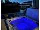 Inviting hot tub with blue lighting sits on a deck with outdoor seating and manicured lawn at dusk at 504 Elizabeth Ave, Platteville, CO 80651
