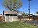 Backyard storage shed with ample green space, mature trees, and privacy fencing at 504 Elizabeth Ave, Platteville, CO 80651