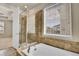 Bathroom showing separate shower and soaking tub with tile surround and bright natural light at 16076 Columbine Pl, Thornton, CO 80602