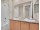Bathroom featuring dual sinks, tub shower, and large mirror at 16076 Columbine Pl, Thornton, CO 80602