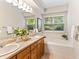Bright bathroom with double sinks, garden tub, and large window offering natural light and relaxing ambiance at 1836 S Kendall Ct, Lakewood, CO 80232