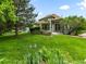Charming home with well-manicured lawn, mature tree, flower beds, and neutral-toned exterior with complementary green trim at 1836 S Kendall Ct, Lakewood, CO 80232