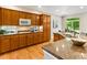 Bright kitchen with wooden cabinetry, granite countertops, and modern appliances, with a view of the dining area at 1836 S Kendall Ct, Lakewood, CO 80232