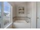 Bright bathroom with a large soaking tub and tiled accent wall at 7036 Orion Ln, Arvada, CO 80007