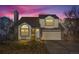 Charming two-story home featuring a well-maintained yard and attached two-car garage at dusk at 10407 Strasburg Way, Parker, CO 80134