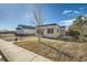 Tan house with dark gray accents, green door, and a sidewalk at 613 Hoover Ave, Fort Lupton, CO 80621