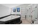 Clean bathroom featuring a jacuzzi tub with a black tile surround, a glass-enclosed shower, and white walls at 772 Garfield St, Denver, CO 80206