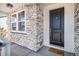 Inviting front porch with stone accents, a classic black door, and a charming 'Wipe Your Paws' doormat at 5381 Hickory Oaks Trl, Castle Rock, CO 80104
