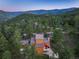 Aerial view of two-story mountain home with a stone chimney, treelined view, and wooded landscape at 207 Kelly E Rd, Boulder, CO 80302