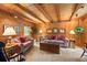 Cozy wooden-paneled living room with beamed ceiling, comfortable seating, and natural light from a window at 207 Kelly E Rd, Boulder, CO 80302