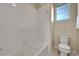 A white tiled shower and a toilet are in a bathroom with a bright window view at 20145 E Fair Ln, Centennial, CO 80016
