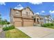 A view of the front exterior of a two-story home with a large concrete driveway, stone accents, and a well-manicured lawn at 20145 E Fair Ln, Centennial, CO 80016