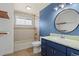 Well-lit bathroom with blue vanity and tiled shower at 2415 E Maplewood Ave, Centennial, CO 80121