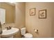 Powder room with pedestal sink, toilet, and decorative wall art, offering a convenient and stylish space at 4784 Raven Run, Broomfield, CO 80023