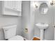 Compact powder room featuring a pedestal sink, toilet, and mirror at 9585 Brentwood Way # D, Westminster, CO 80021