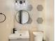 Stylish bathroom featuring hexagon tiles, a round mirror, and modern fixtures at 5470 Danube St, Denver, CO 80249